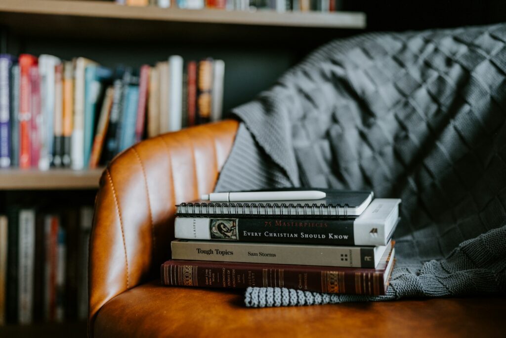 a stack of books sitting on top of a brown chair